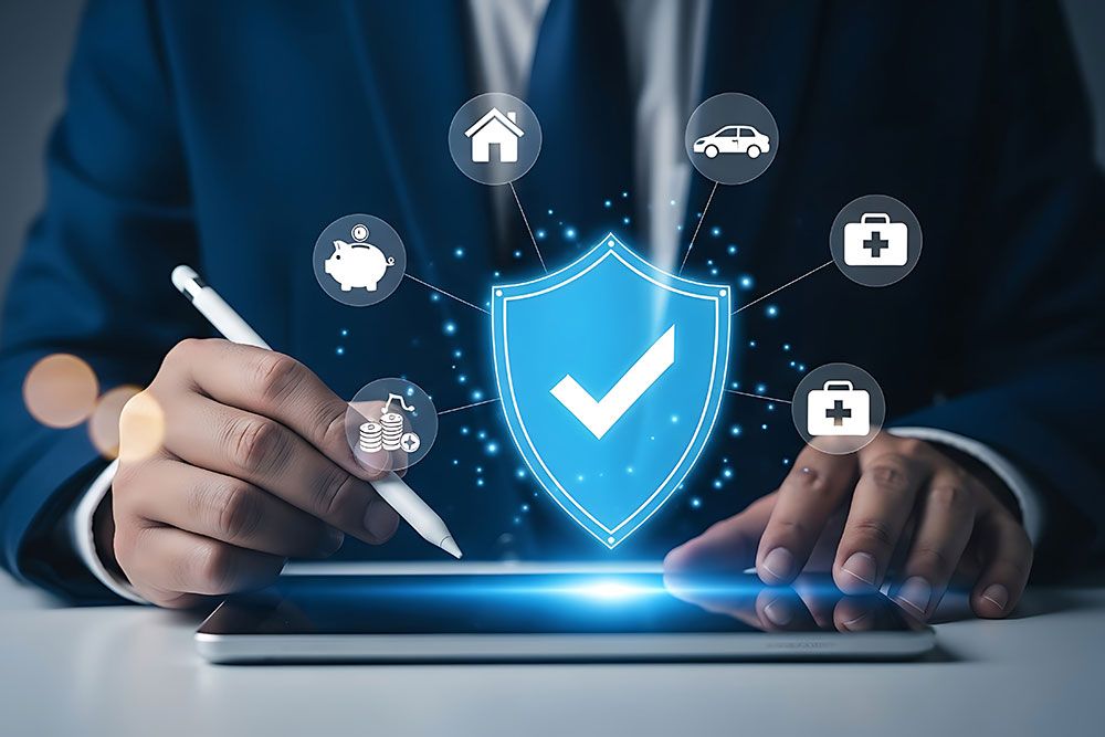 Close-up of a professional reviewing insurance coverage on a tablet, with a glowing shield and icons representing home, auto, health, and financial protection.