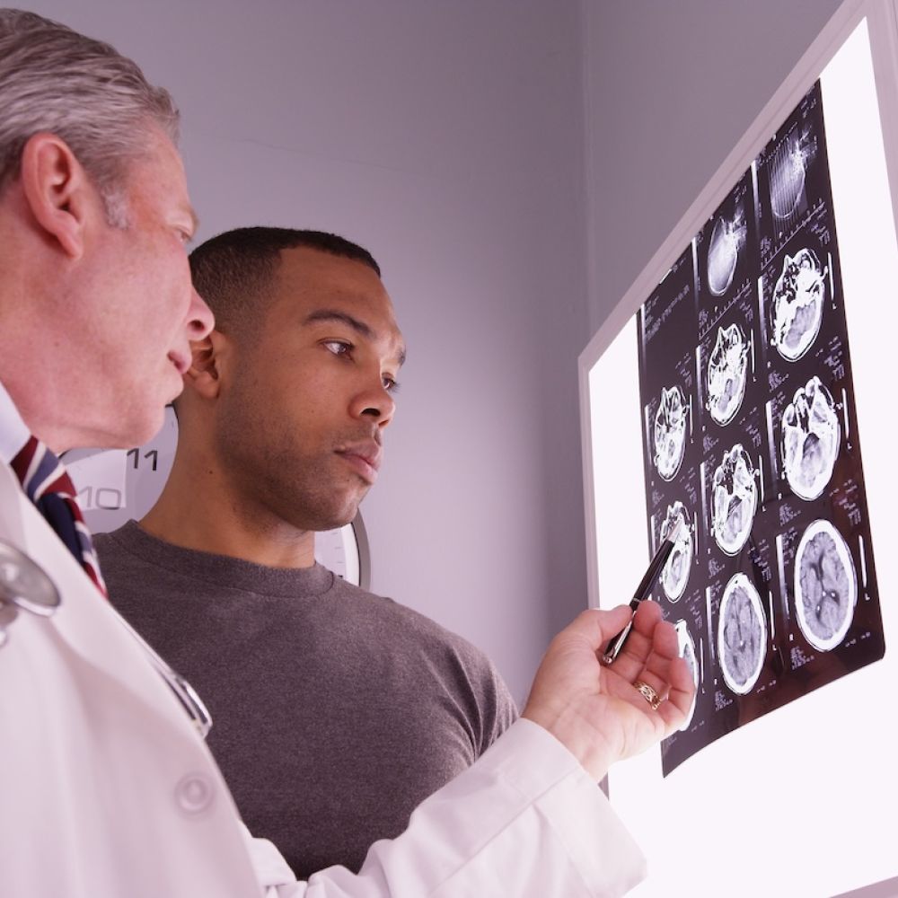 Doctor discussing MRI brain scans with patient in a medical office.