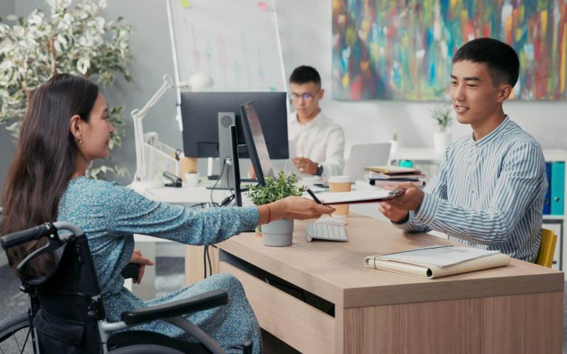 a man in a wheelchair handing something to a woman