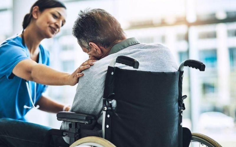 Nurse assisting man in wheelchair