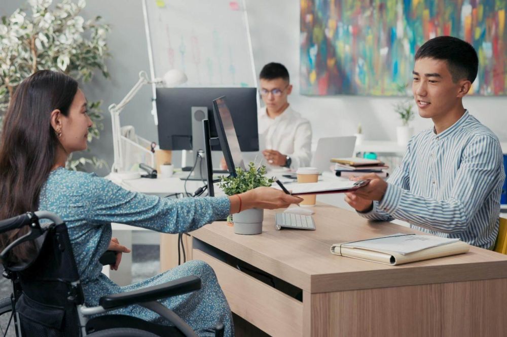 a man in a wheelchair handing something to a woman