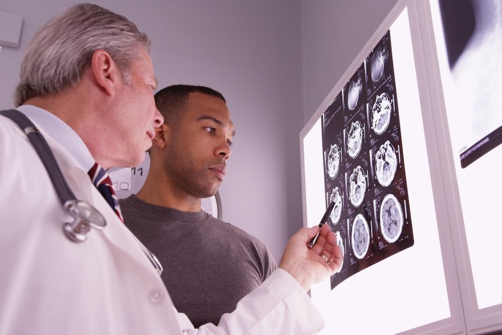 Doctor discussing MRI brain scans with patient in a medical office.