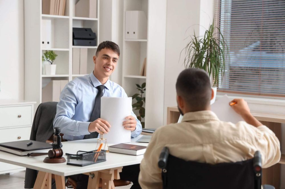 a man sitting at a desk in front of a man holding a piece of paper