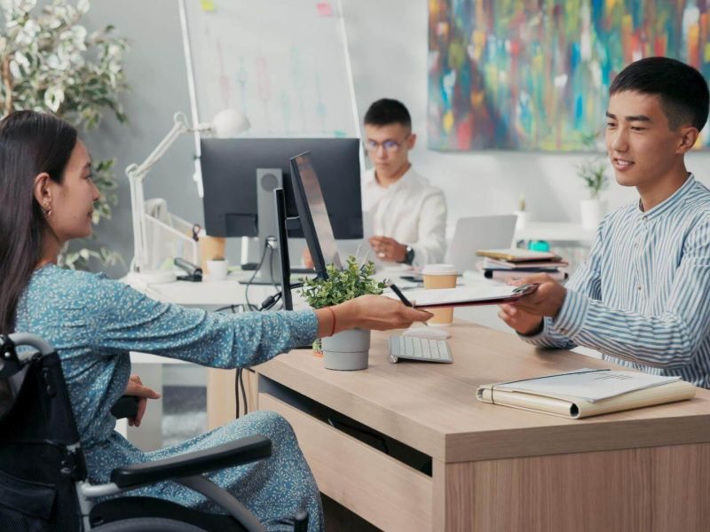a man in a wheelchair handing something to a woman