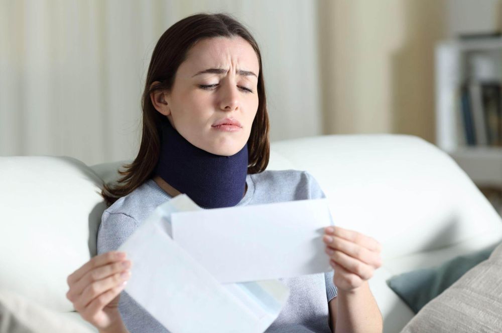 a woman with a neck collar sitting on a couch holding a piece of paper