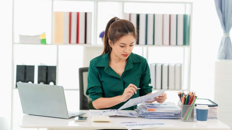 a woman sitting at a desk with a laptop and papers