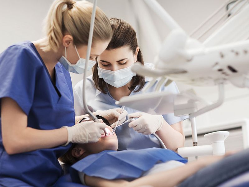 Dentists performing a dental procedure on a patient in a clinic.