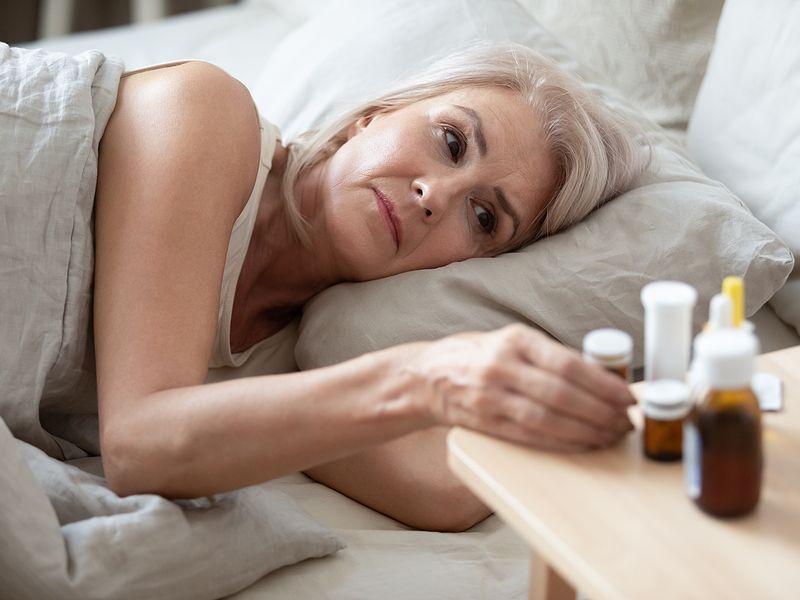 Unhealthy Older Woman Taking Pills From Bedside Table Close Up