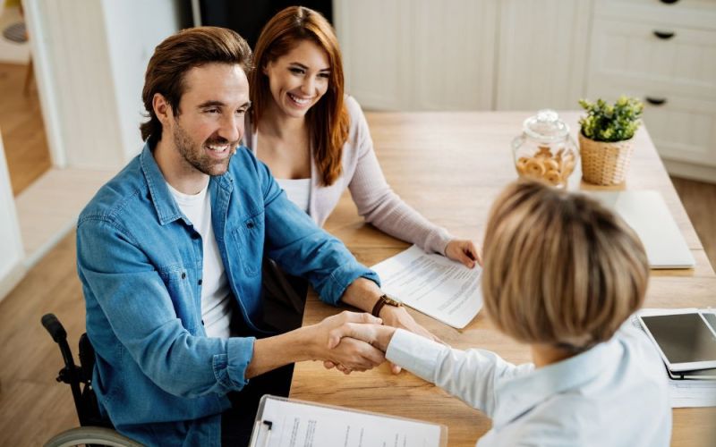 Man in a wheelchair shaking hands with his long-term disability attorney after getting benefits restored.