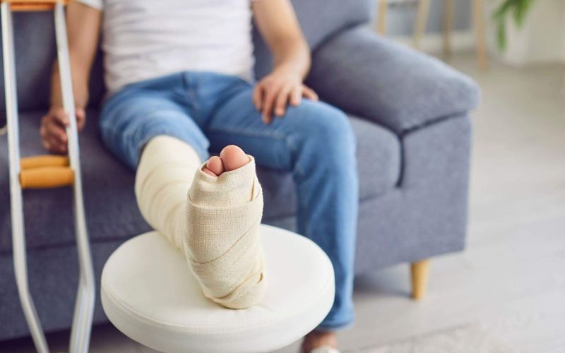 a person with a cast on their foot sitting on a couch