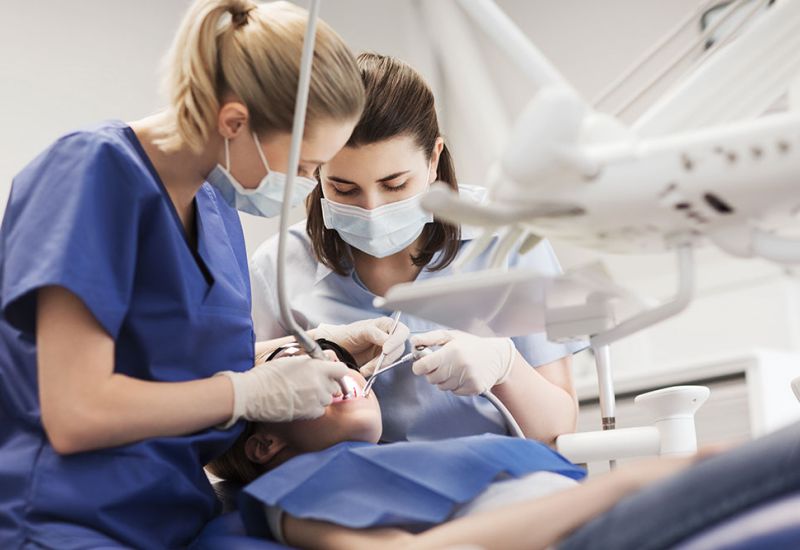 Dentists performing a dental procedure on a patient in a clinic.