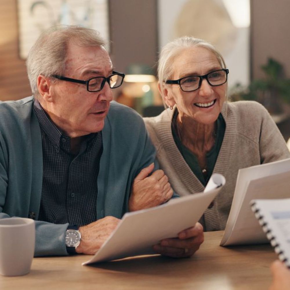 an elderly couple is engaged in conversation with another person holding documents