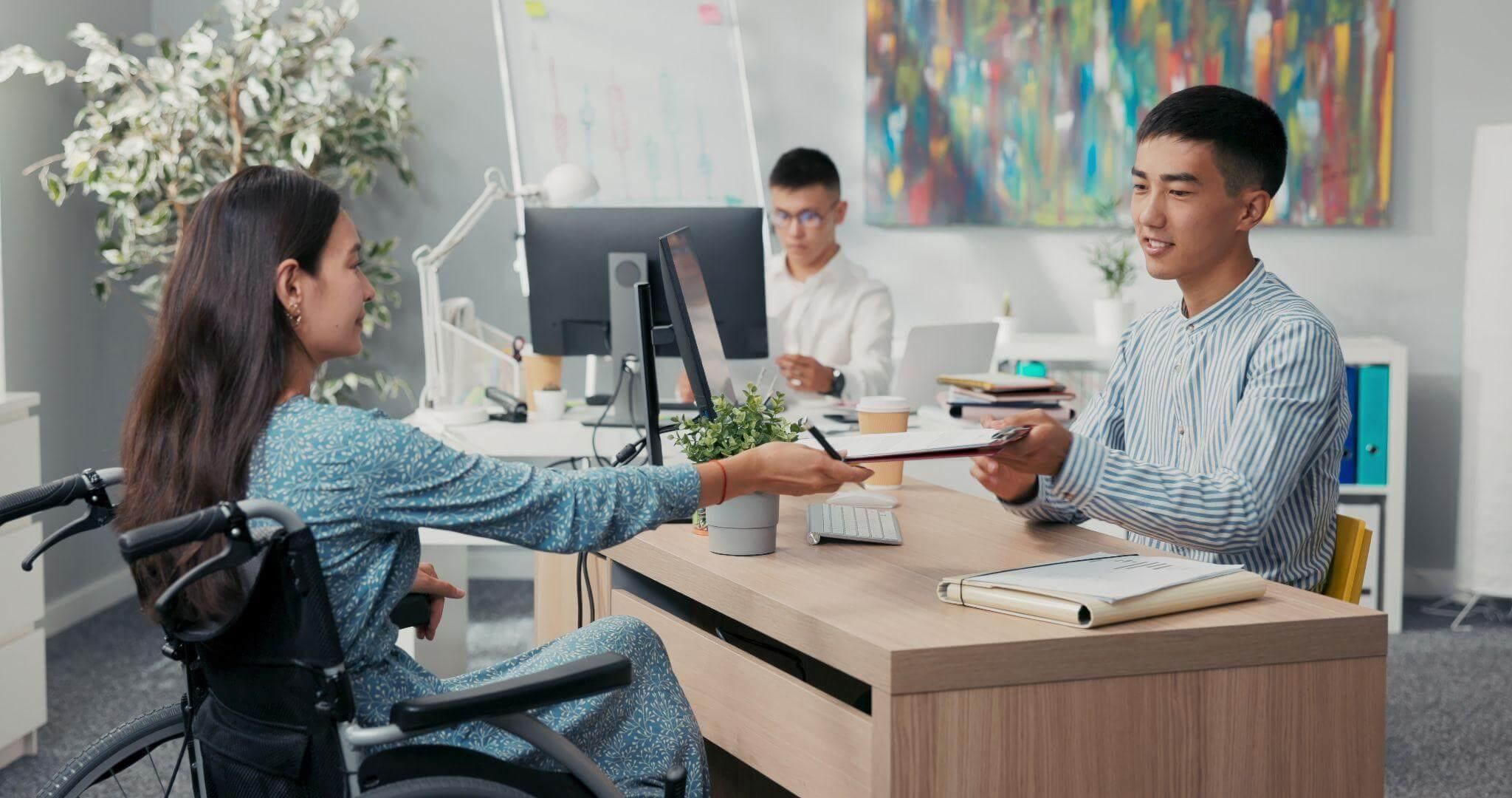 a man in a wheelchair handing something to a woman