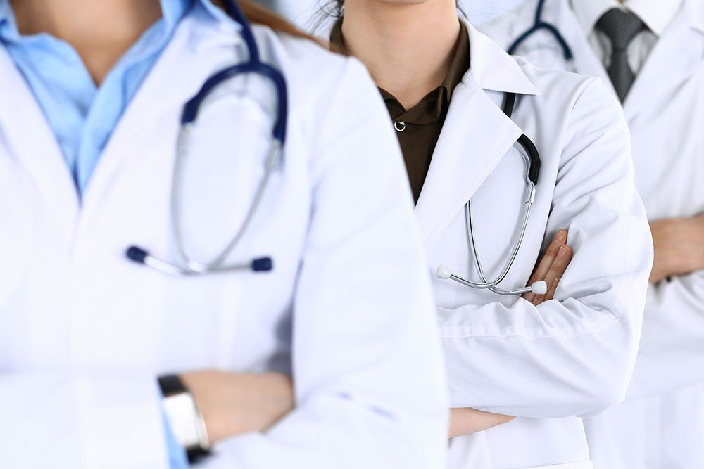 Doctors in white coats with stethoscopes standing confidently, symbolizing teamwork and healthcare professionalism.