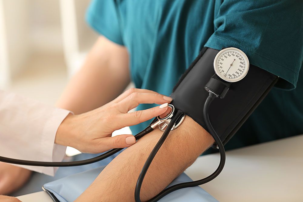 Healthcare worker measuring blood pressure with a sphygmomanometer on a patient's arm for health checkup.