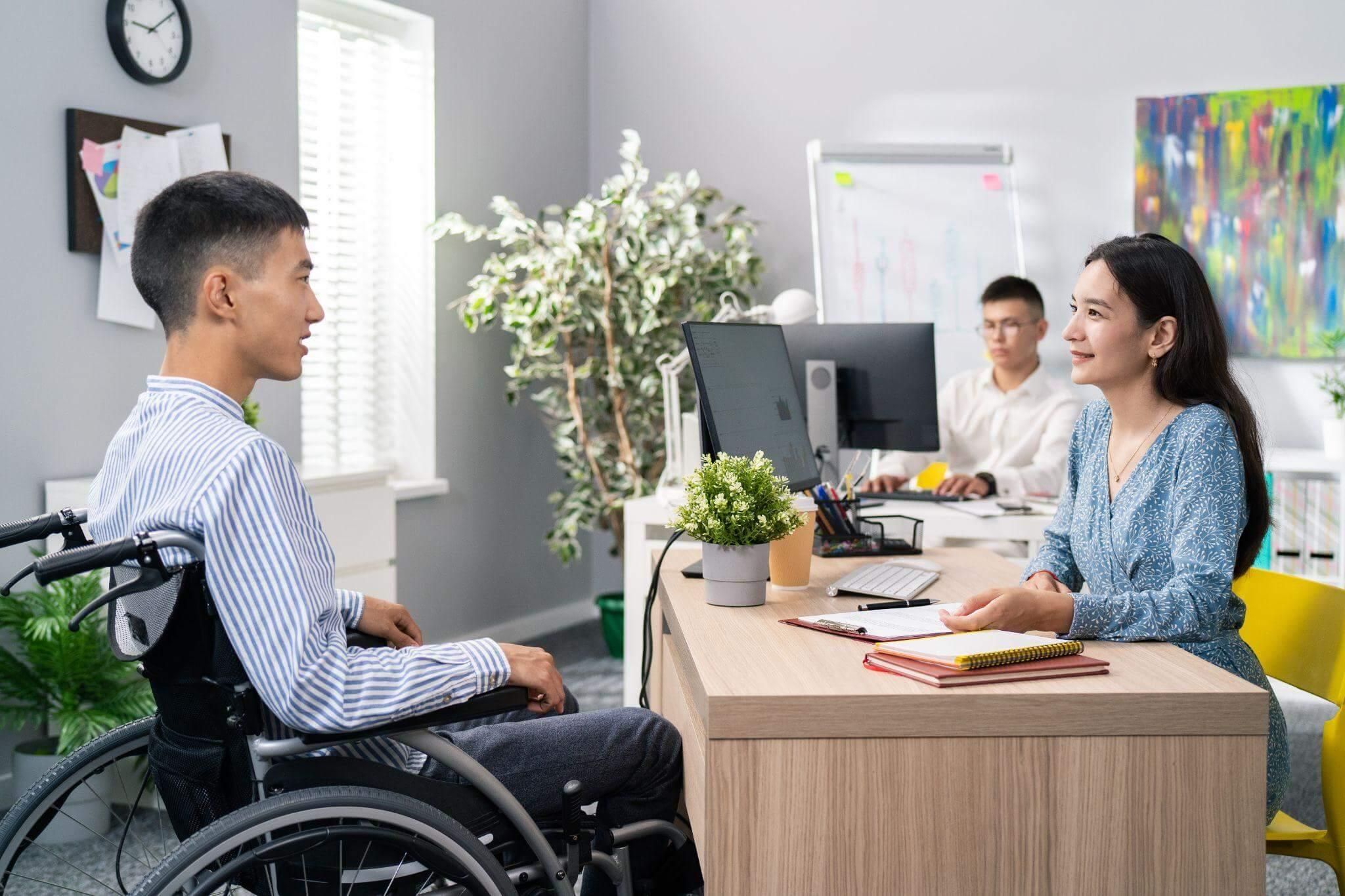 a man in a wheel chair talking to a woman in a wheelchair