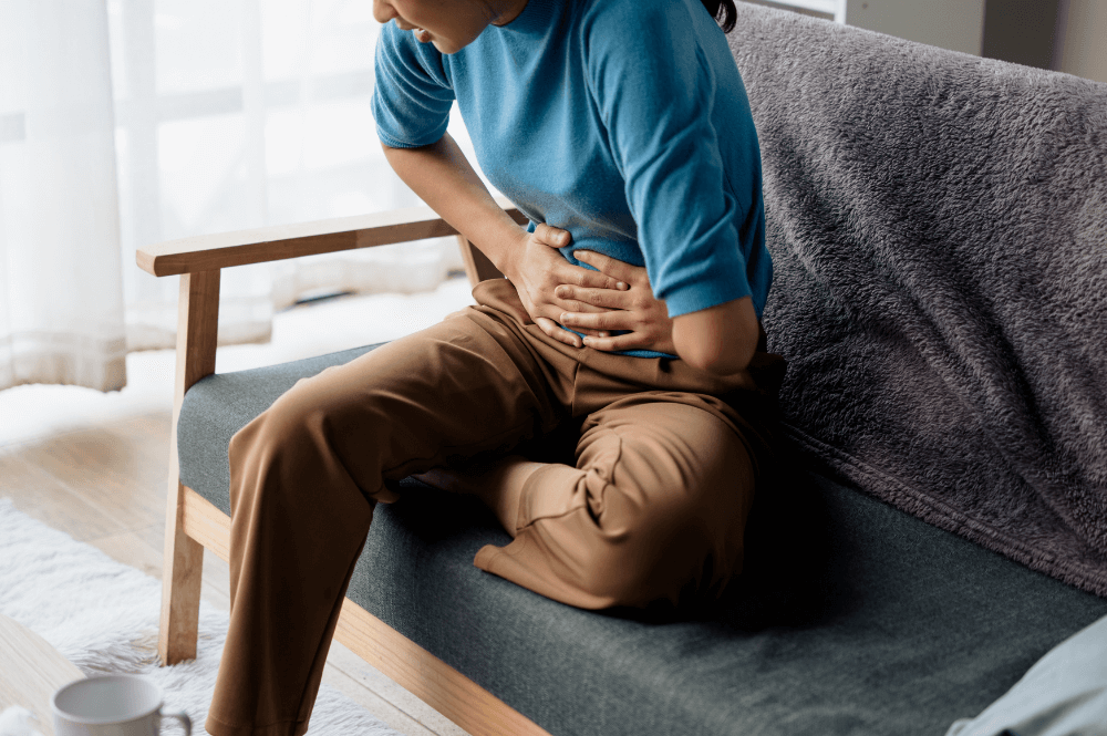a woman sitting on a couch holding her stomach