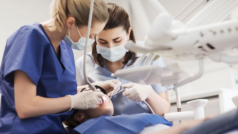 Dentists performing a dental procedure on a patient in a clinic.