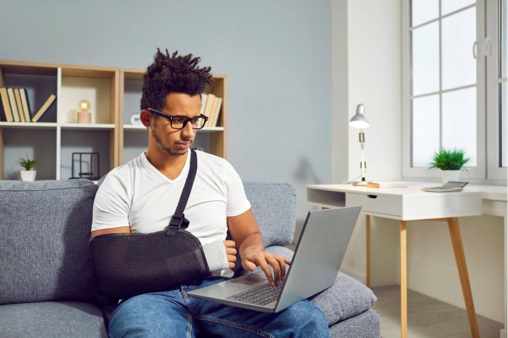man on his laptop with arm in a sling due to a short term disability