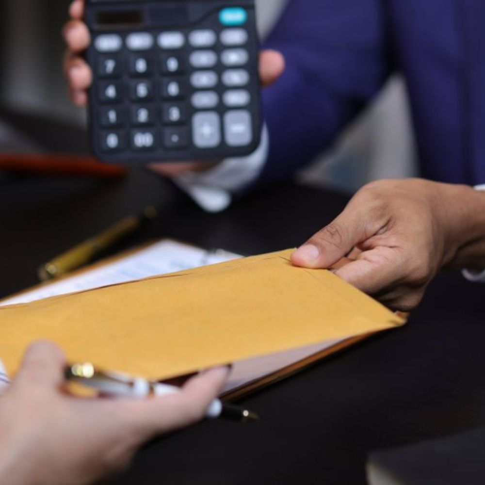 two people negotiation, one is handing a folder and another is holding a calculator