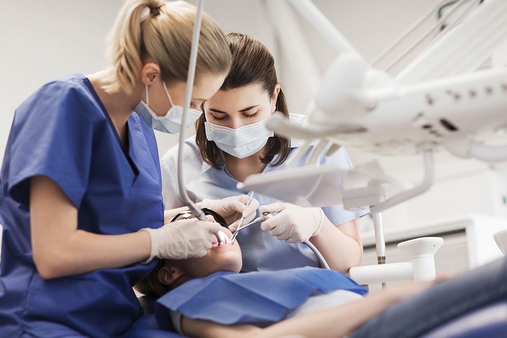 Dentists performing a dental procedure on a patient in a clinic.
