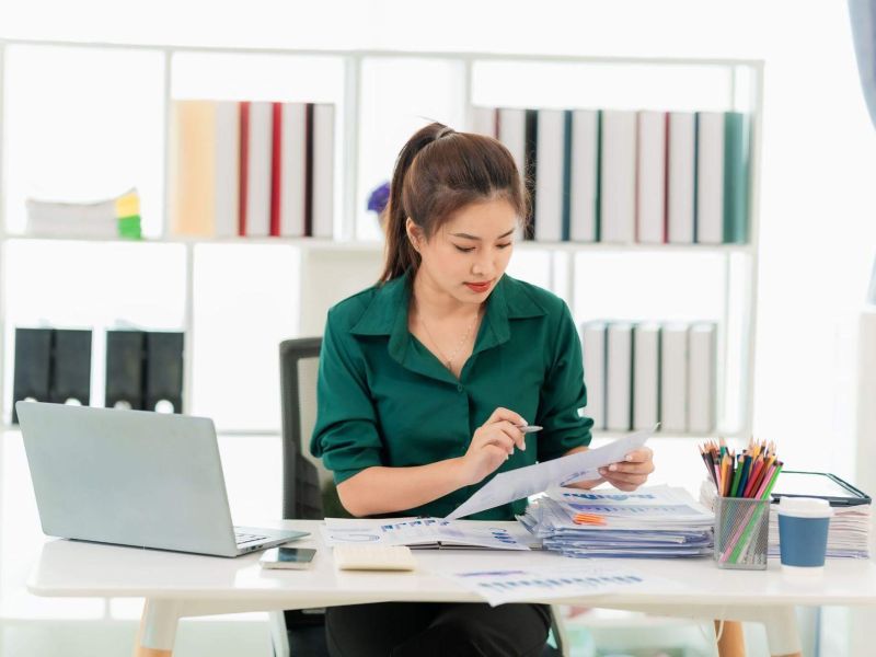 a woman sitting at a desk with a laptop and papers