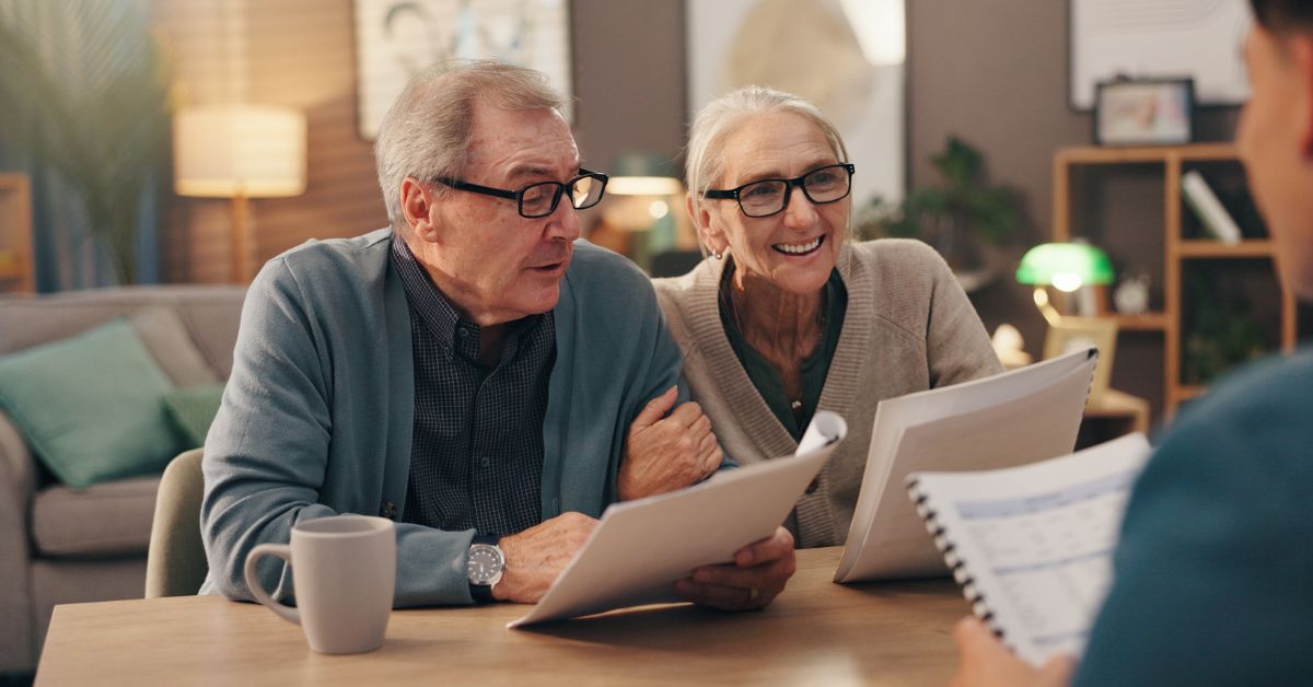 an elderly couple is engaged in conversation with another person holding documents