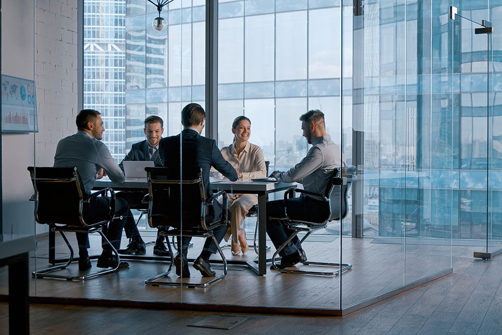A diverse group of professionals having a meeting in a modern office conference room with city views.