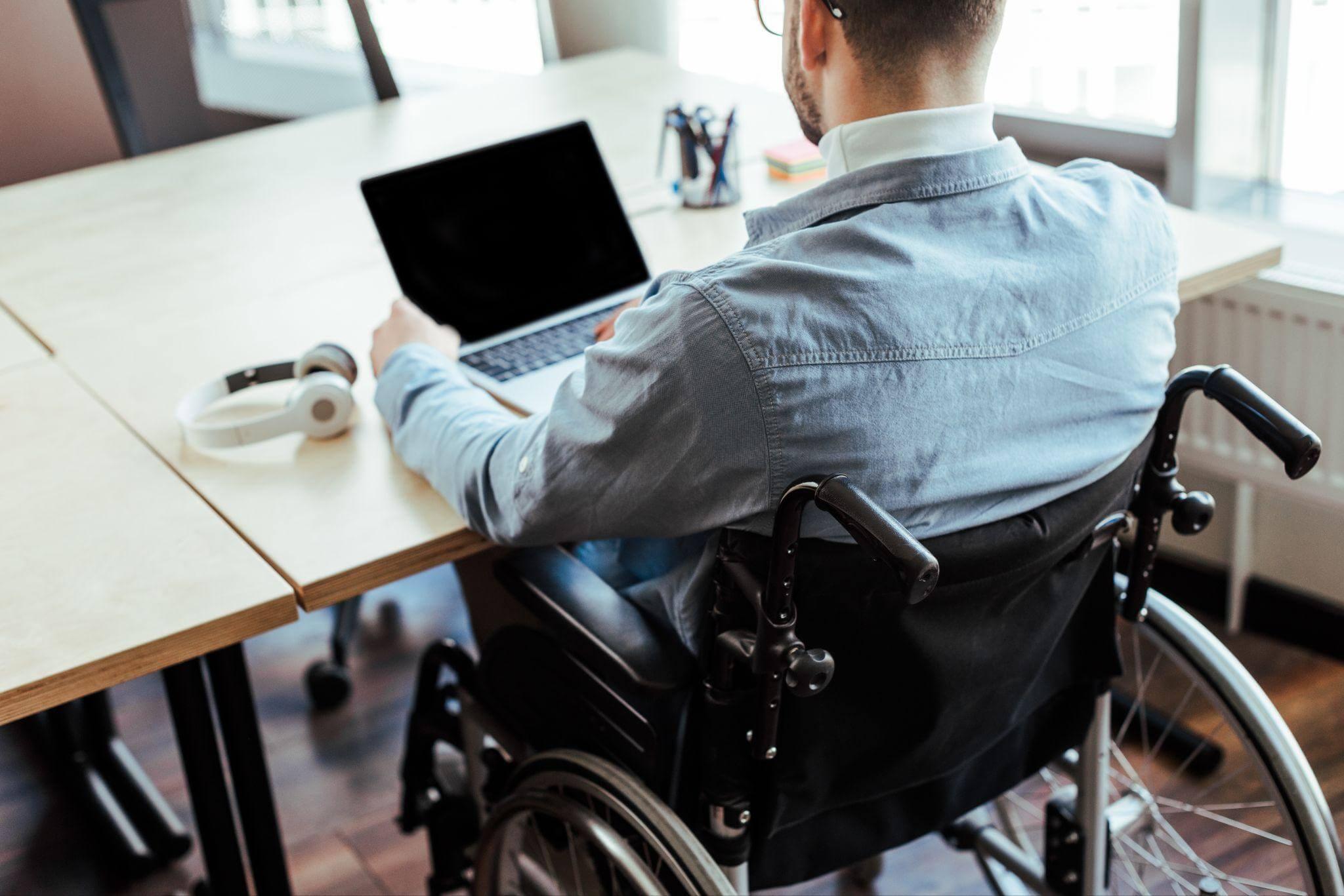 a man in a wheelchair using a laptop computer