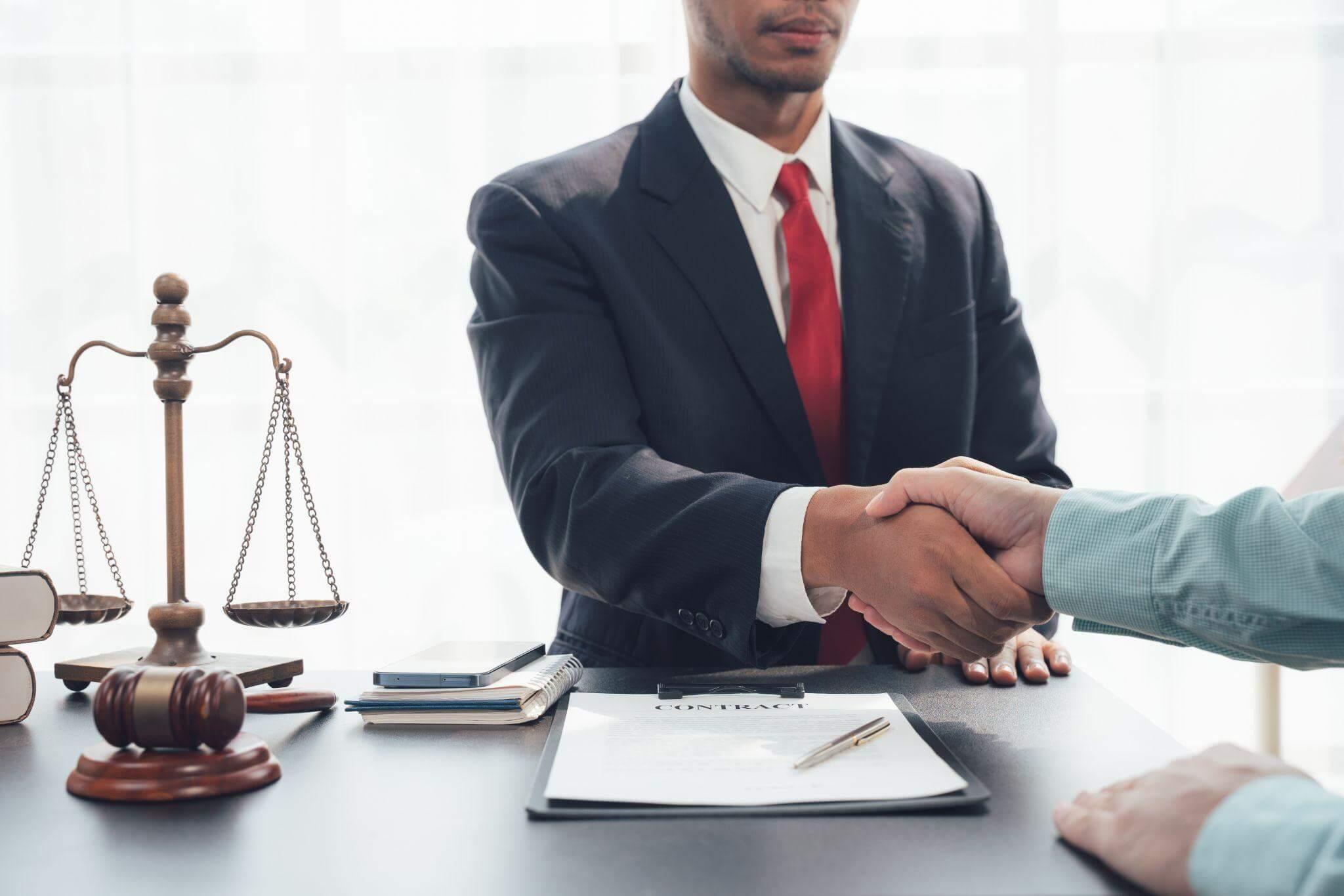 two men shaking hands in front of a scale of justice