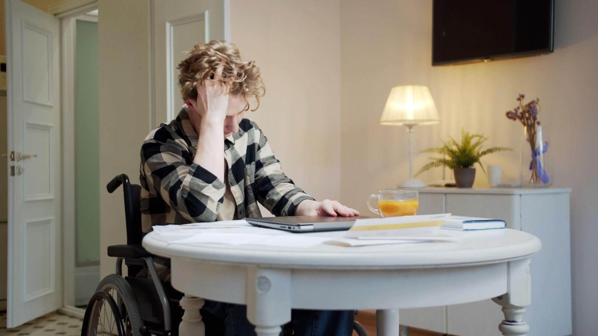a person in a wheelchair next to a table with a laptop