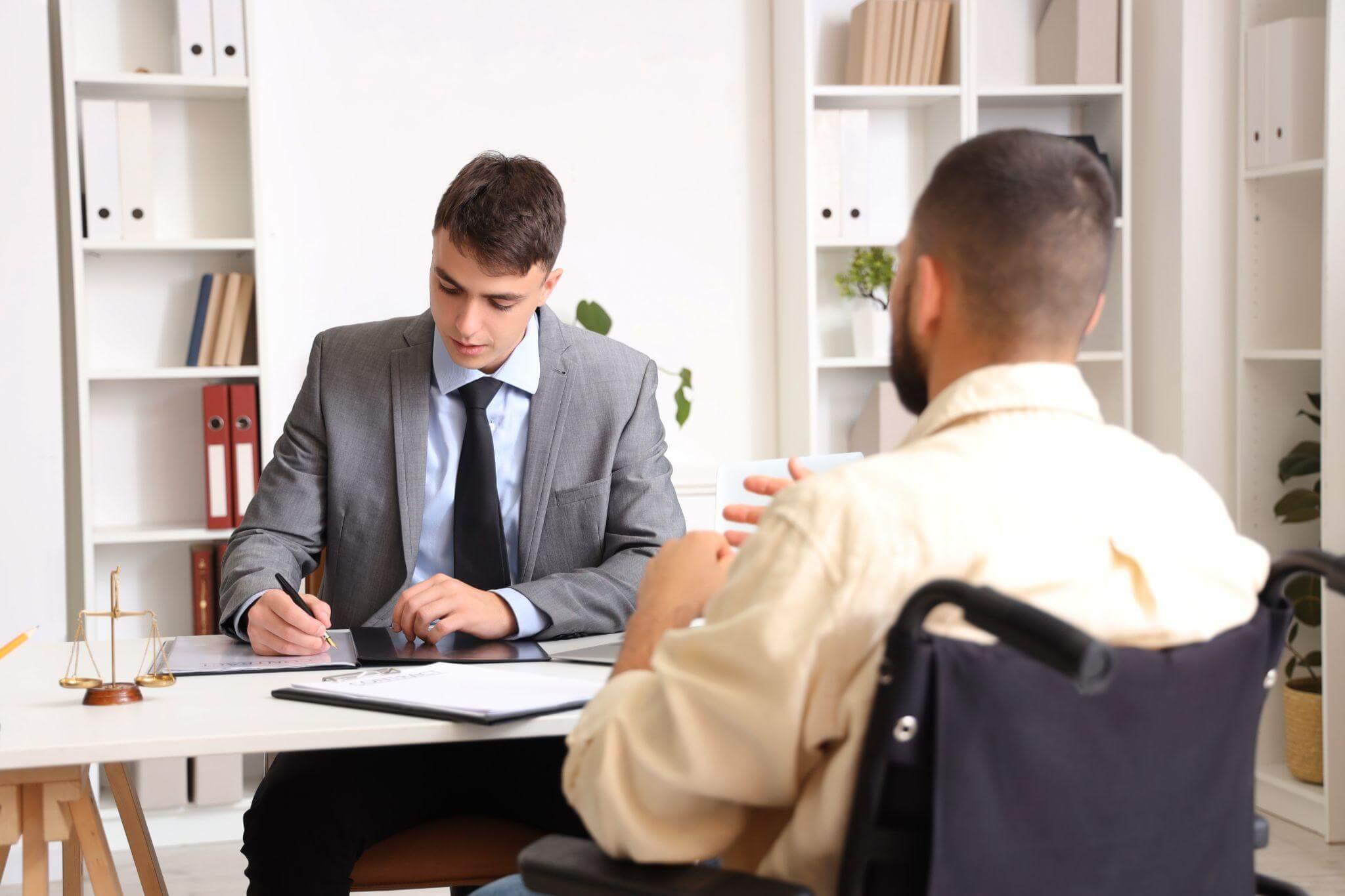a man sitting at a desk in front of a man in a suit, they are reviewing legal matters