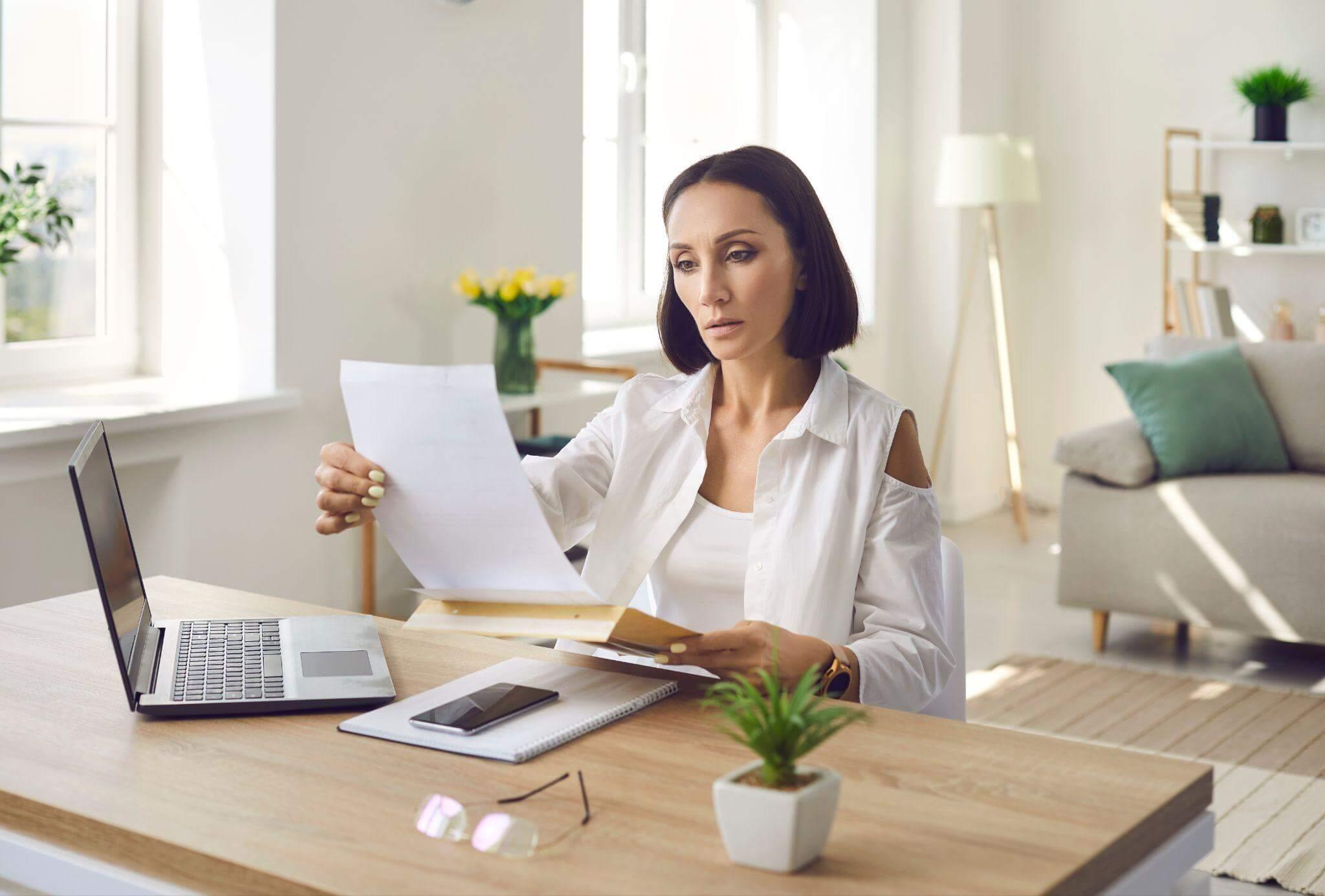 a woman sitting at a desk with a laptop and papers