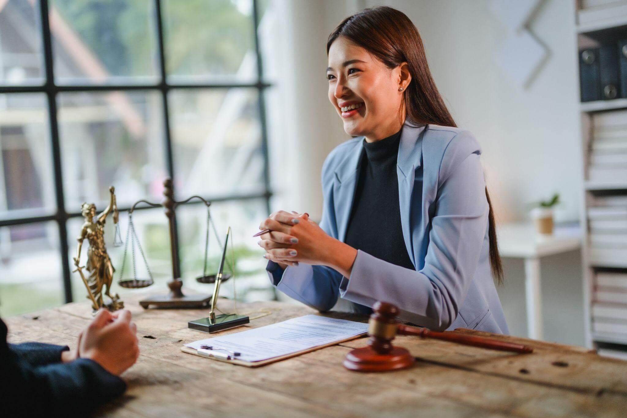 a woman sitting at a table in front of a scale of justice