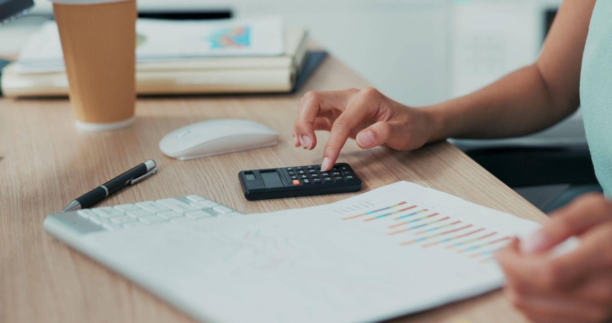 a person sitting at a desk using a calculator