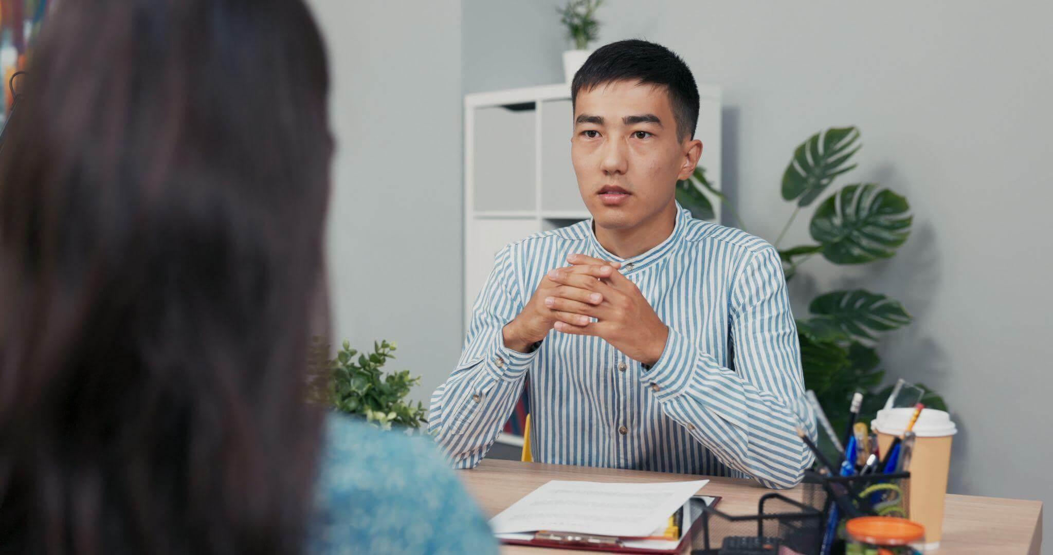 a man sitting at a desk in front of a woman
