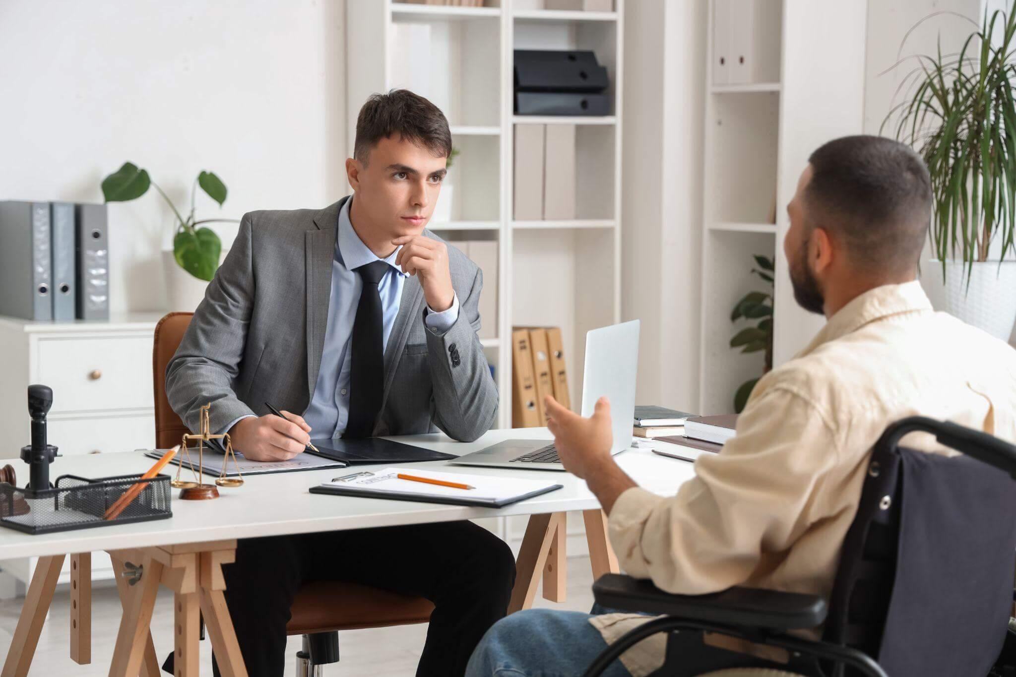 a man sitting at a desk talking to another man