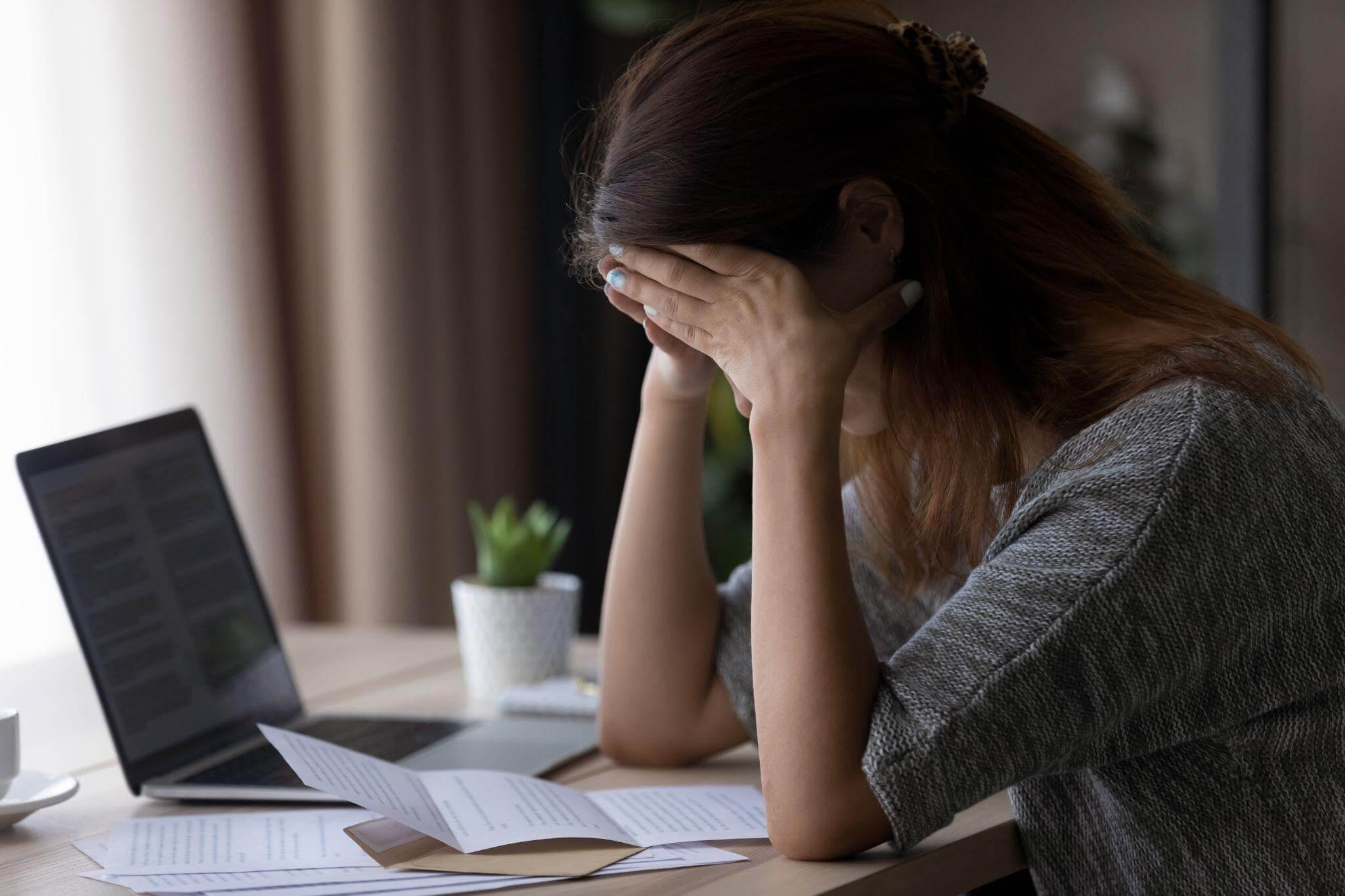 a woman sitting at a desk with her head in her hands