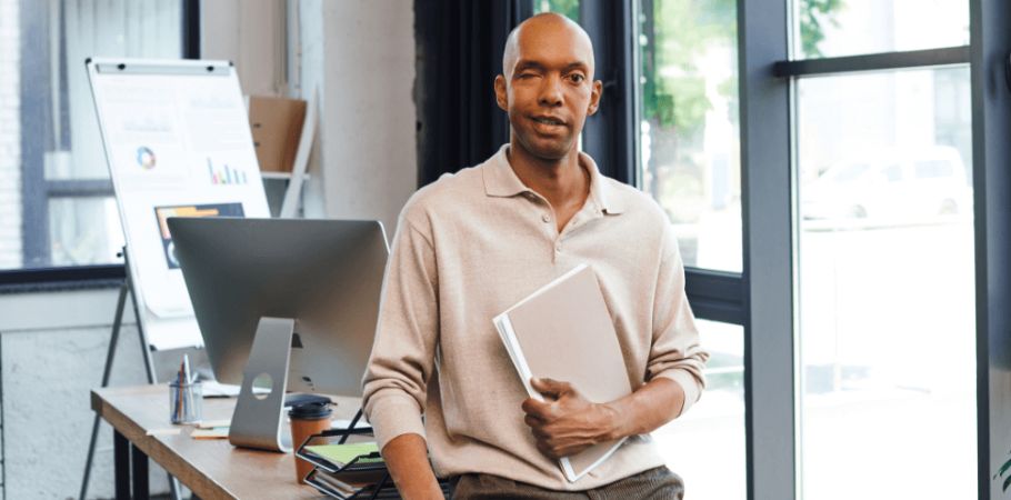 man in an office holding his laptop