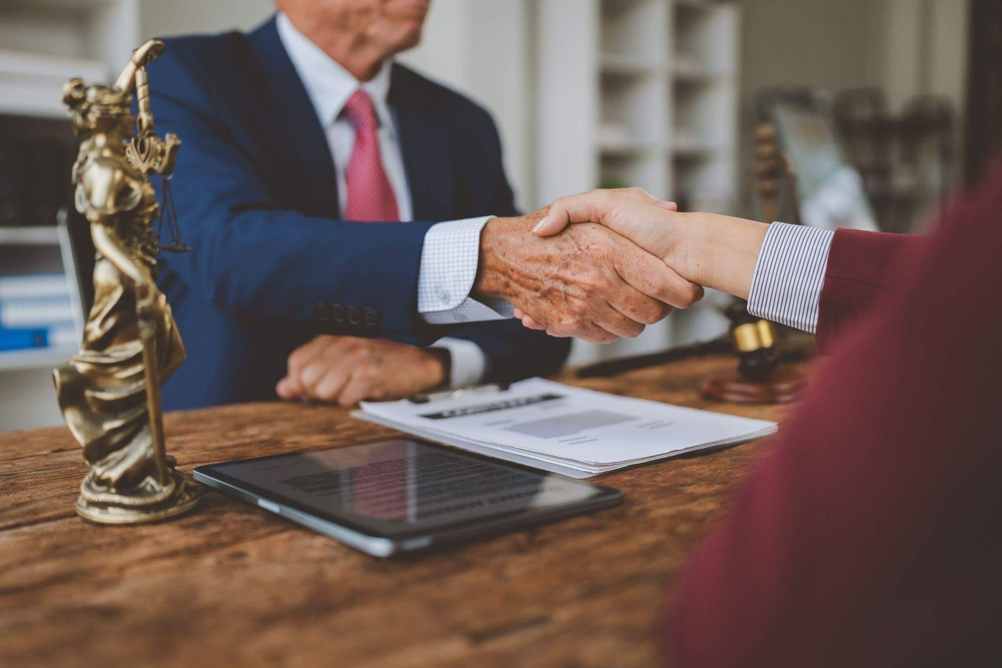 two people shaking hands over a tablet computer