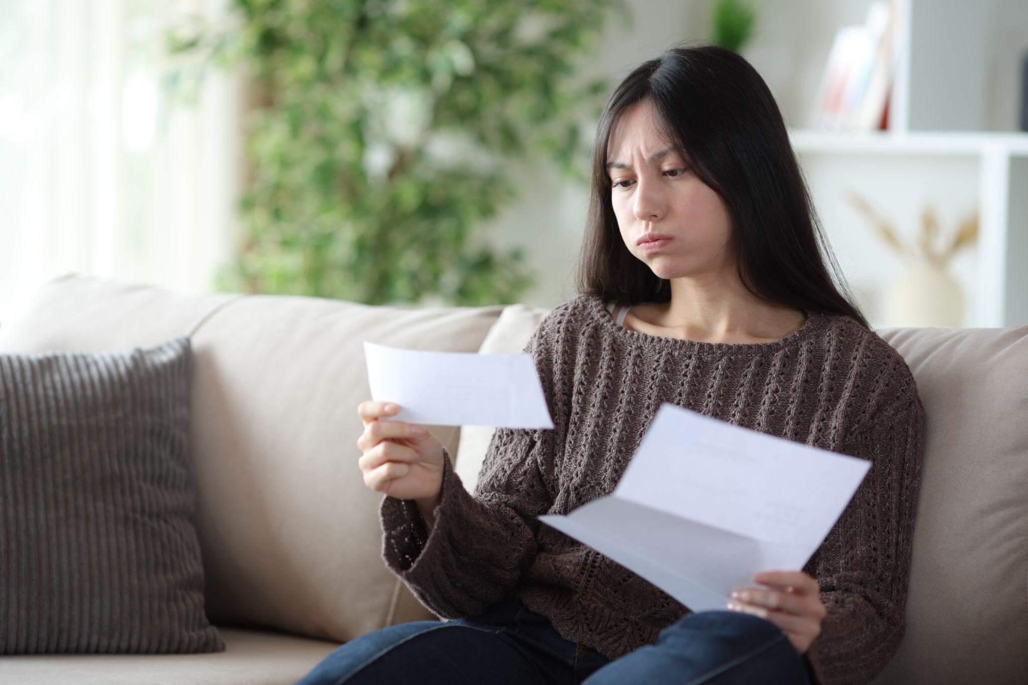 Woman on couch holding paper, possibly